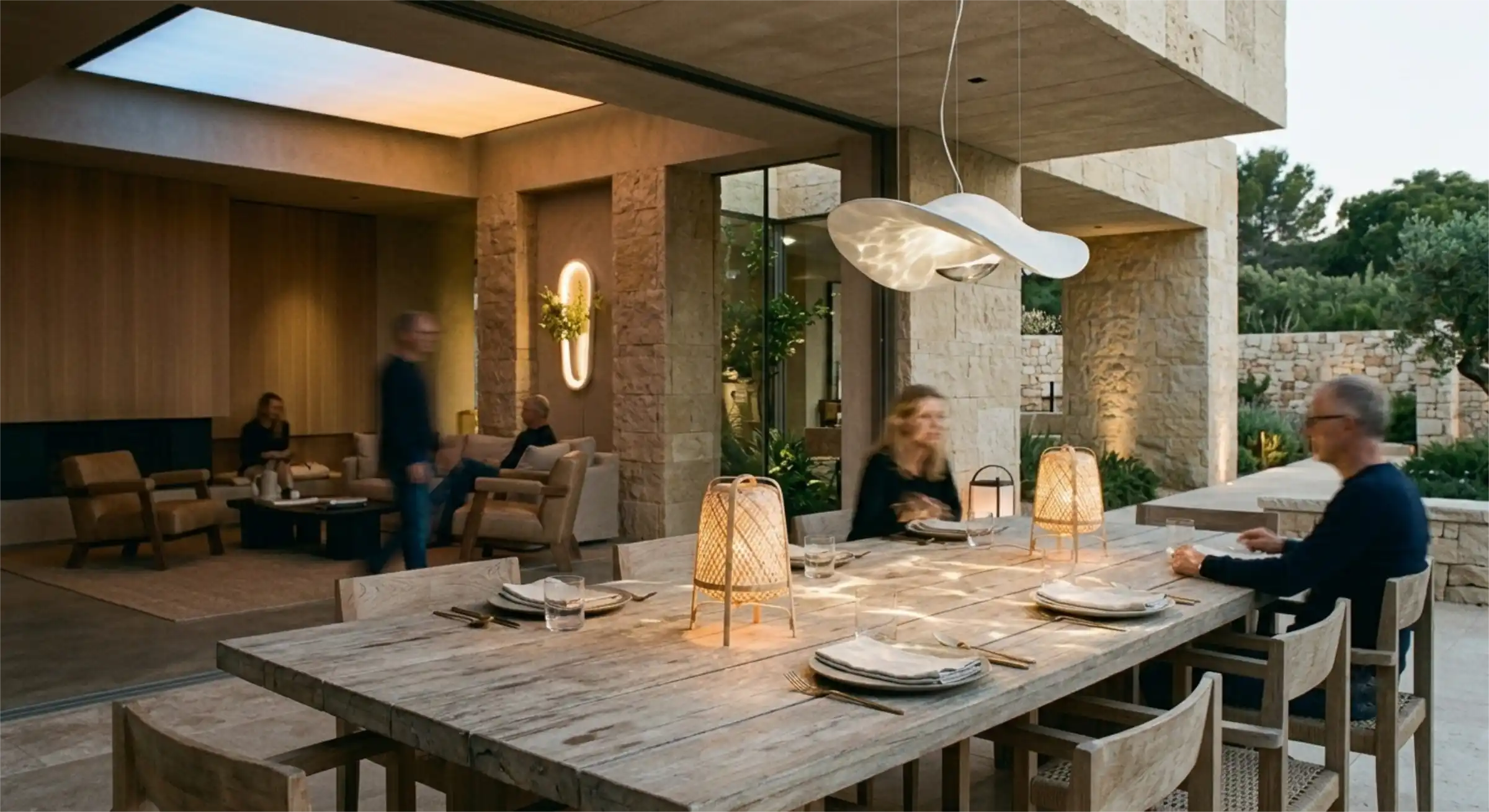 A sunlit modern interior featuring a central glass-enclosed pocket garden and warm bamboo pendant lamps.